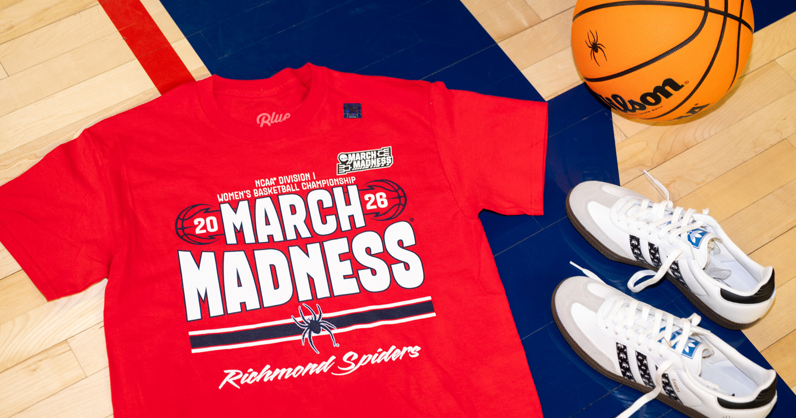 Image our new basketball tee surrounded by shoes and a basketball on a basketball court.